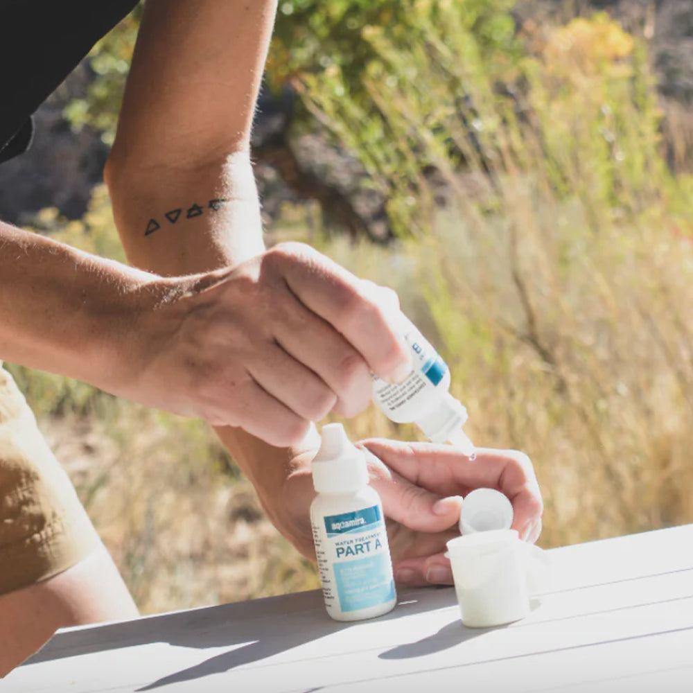 Woman treating drinking water with Aquamira Water Treatment Drops