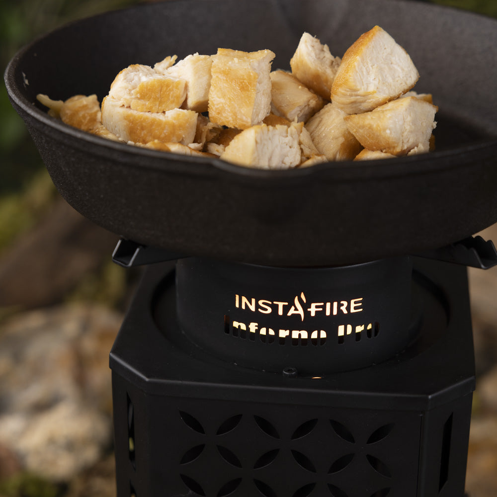 InstaFire Inferno Pro Outdoor Biomass Stove cooking chicken in a cast iron pan outdoors