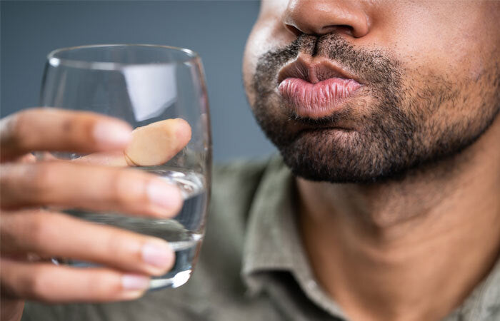 man holding a cup with a mouth full of water