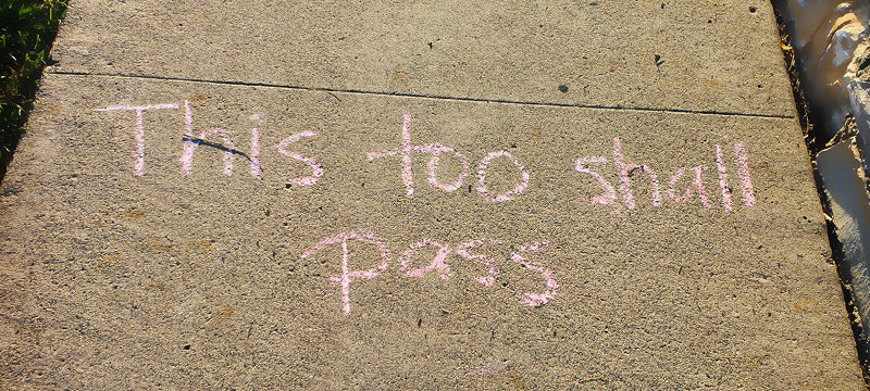 Sidewalk chalk writing "this too shall pass"