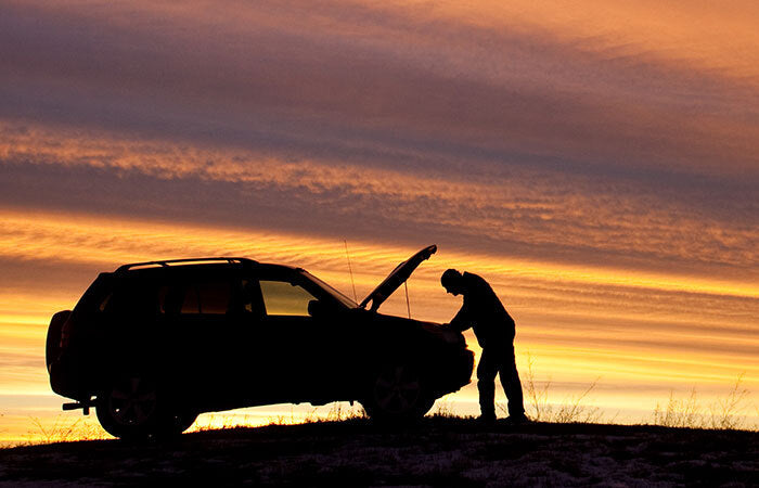 Person looking at broken down car