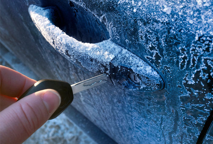 Person inserting key into frozen car door lock