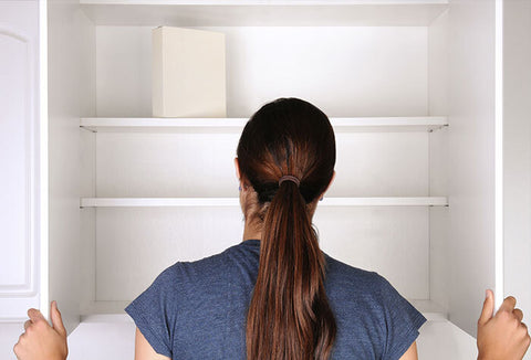 Woman standing in front of empty pantry shelves.