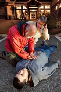 Older man oerforming CPR on a young man.