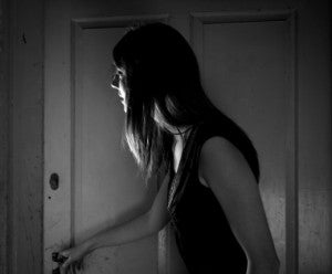 black and white photo of a young woman opening a door