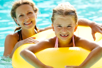 Mother and daughter swimming in pool with inner tube