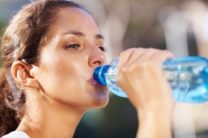 brunette woman drinking water from a bottle on a warm day